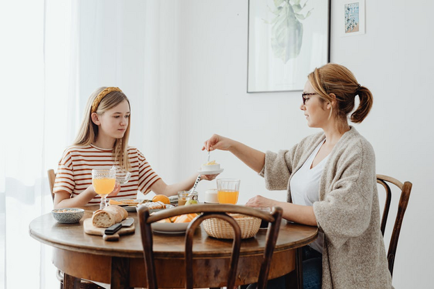 Free Woman and a Girl Eating Sweet Breakfast at a Wooden Table Stock Photo