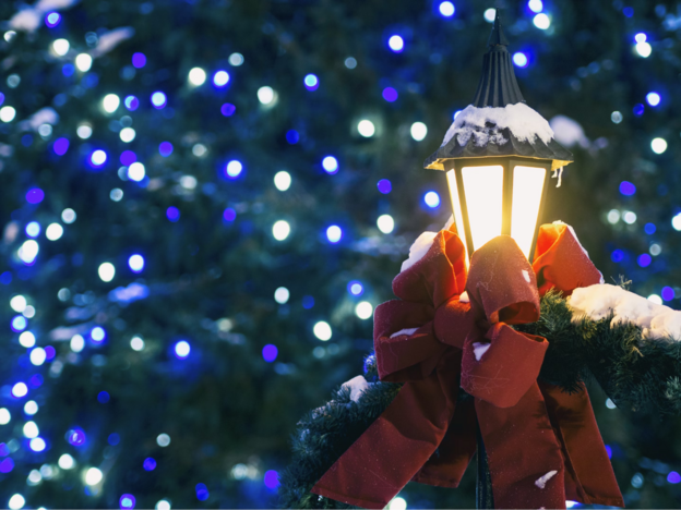 A lamp post with ribbon and Christmas lights on the background 