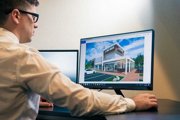 a man sitting at a desk looking at a computer screen